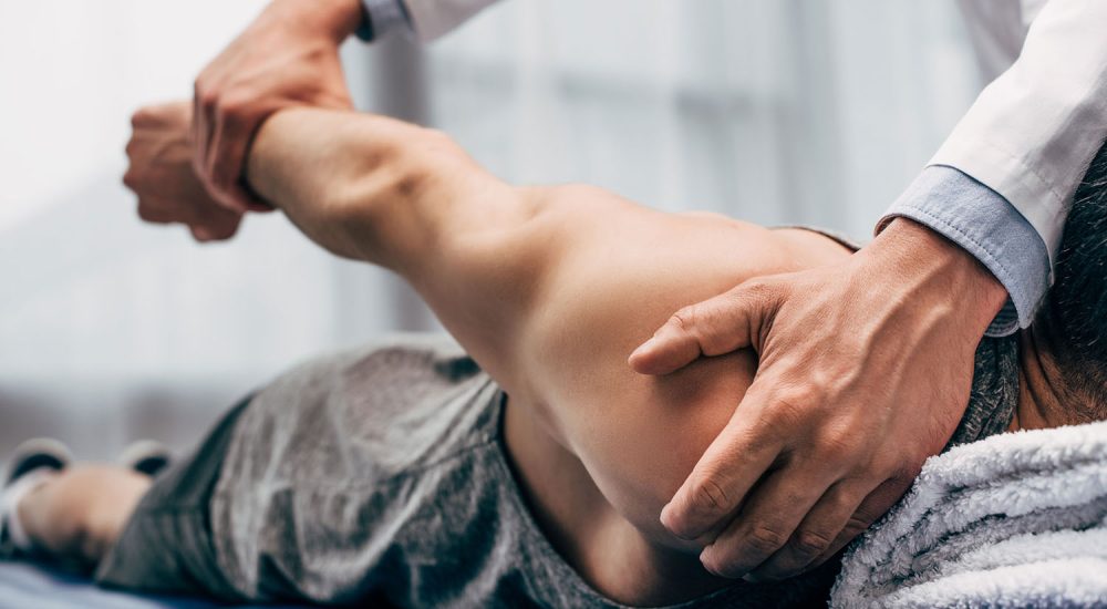 selective focus of chiropractor stretching arm of patient in hos